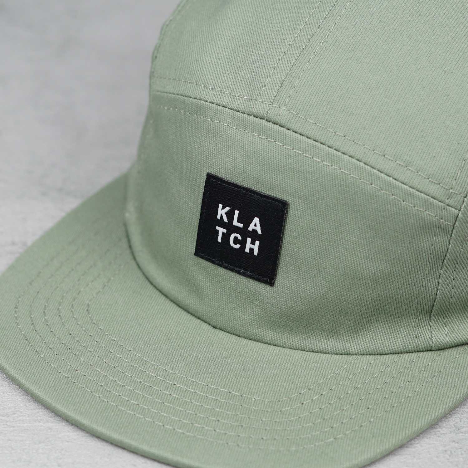woven label on green five panel hat